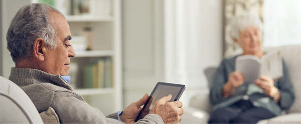 Elderly couple reading a book and a tablet